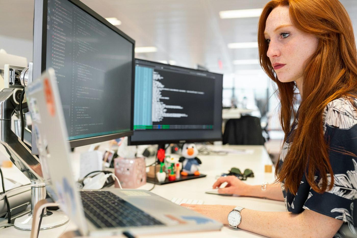 A software engineer reading code across two monitors at an office desk